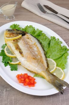 Baked fish Dorado in lettuce leaves with lemon