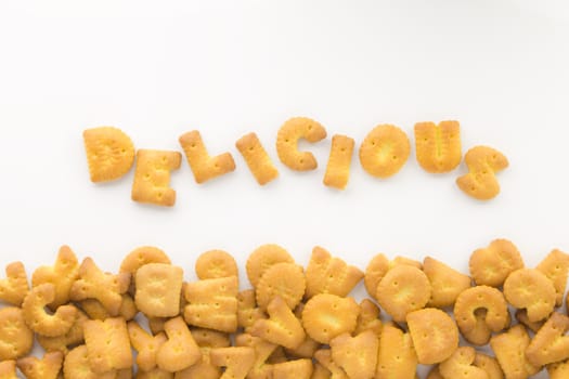 Top view of letter cookies the word DELICIOUS and group of mix alphabet biscuits putting on white background.