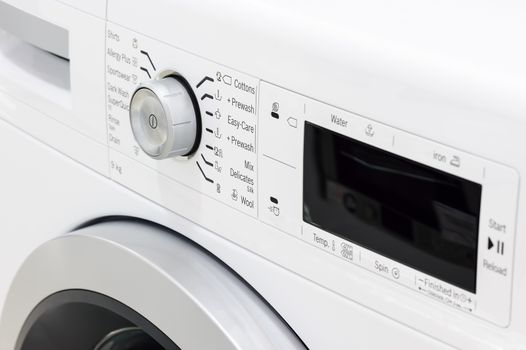 closeup of new white laundry or washing machine, selective focus on control elements
