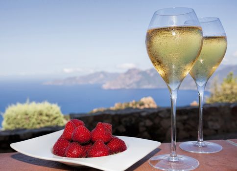 romantic drink for two near the sea in corsica, with strawberries and white wine in two glasses