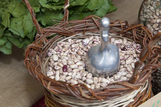 red beans in wicker basket, in market, organic vegetables in the background