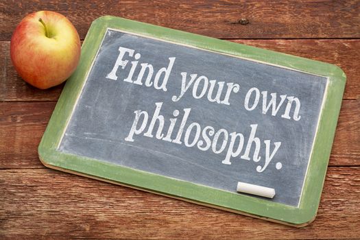 Find your own philosophy - motivational words on a slate blackboard against red barn wood