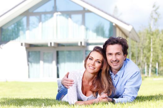 happy couple lying in front of their house