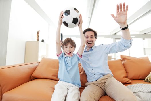 father and son wathcing football inside their house