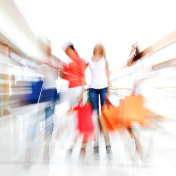 Women walking fast in shopping mall with bags