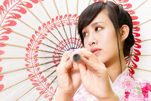 Asian woman wearing a kimono holding umbrella