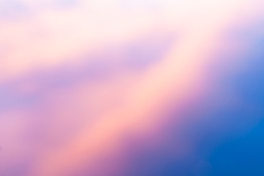 Sunset colored clouds reflecting in calm water abstract background colors transition pale pink through beep blue diagonally.