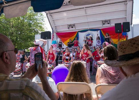 Nyack, NY, USA - June 14, 2015: Members of Batala NYC performing on and before the stage during Rockland County Pride. Observer taking pictures with the phone.