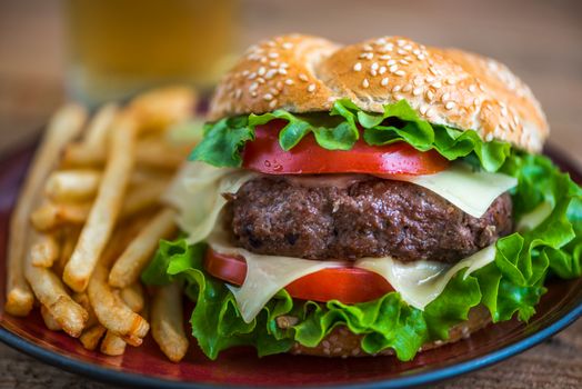 Closeup of Homemade Hamburger with Fresh Vegetables and French Fries on a Plate