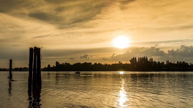 Sunset over the Fraser River looking west with tie downs for log booms in the foreground