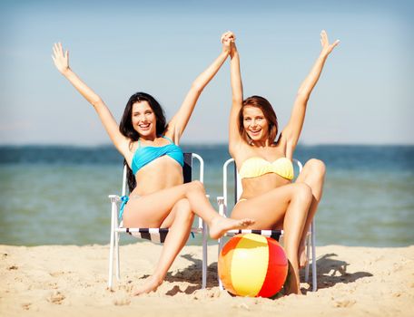 summer holidays and vacation - girls in bikinis sunbathing on the beach chairs
