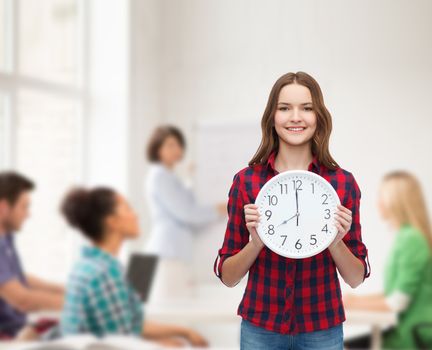 happiness and people concept - smiling young woman in casual clothes with wall clock showing 8 oclock
