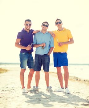 summer, holidays, vacation, happy people concept - group of friends having fun on the beach with bottles of beer or non-alcoholic drinks