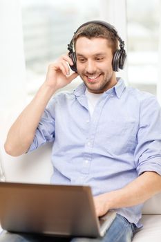 technology, home, music and lifestyle concept - smiling man with laptop and headphones at home