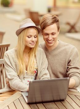 technology concept - couple with laptop in cafe