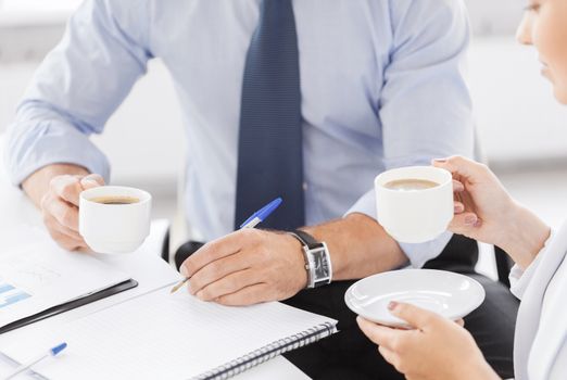 business, school and education concept - smiling businesswoman and businessman discussing something in office