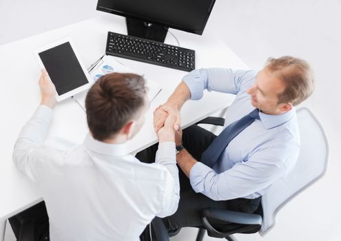 business, technology and office concept - businessmen shaking hands in office