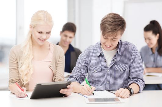 education, technology and internet - two smiling students with tablet pc and notebooks