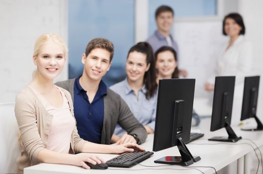 education, technology and internet concept - students with computer monitor at school