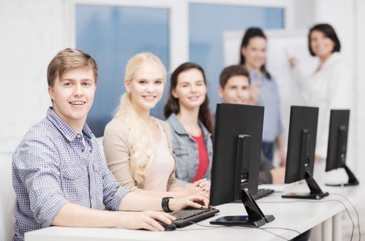 education, technology and internet concept - students with computer monitor at school