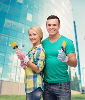 repair, construction and maintenance concept - smiling couple with paintbrush