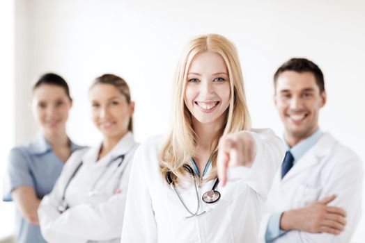 healthcare and medical concept - attractive female doctor in front of medical group