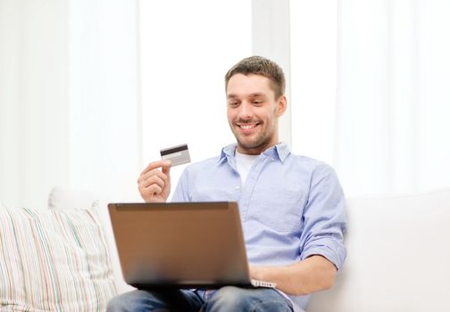 technology, home and lifestyle concept - smiling man working with laptop and credit card at home