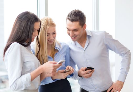 business and technology concept - smiling business team with smartphones in office