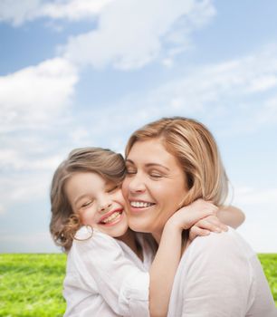 family, child and happiness concept - hugging mother and daughter