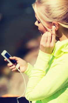 sport and lifestyle concept - woman doing sports and listening to music outdoors