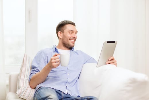 lifestyle and technology concept - smiling man working with tablet pc at home