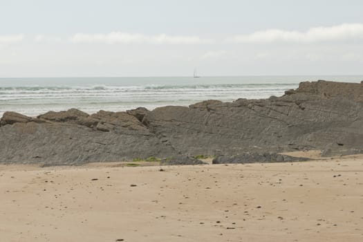 A beach, an ocean with a sailboat in the background