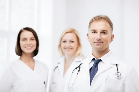 healthcare and medical concept - male doctor with stethoscope and colleagues