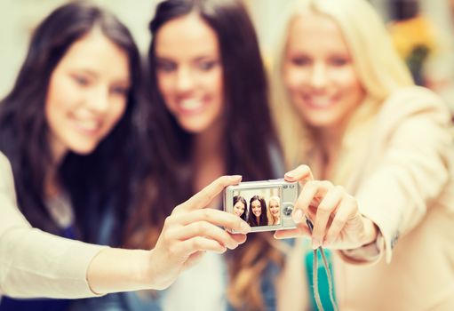 holidays and tourism, modern technology concept - beautiful girls taking picture in the city