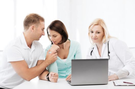 healthcare, medical and technology concept - doctor with patients looking at laptop