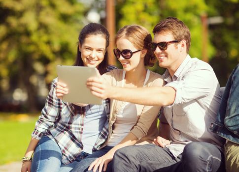 summer, internet, social networking and teenage concept - group of teenagers taking photo with tablet pc outside