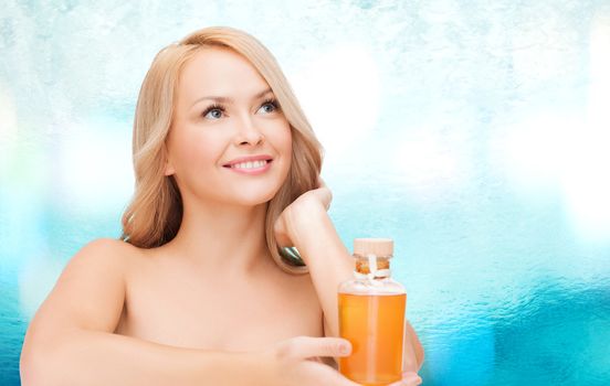 health and beauty concept - happy woman with oil bottle