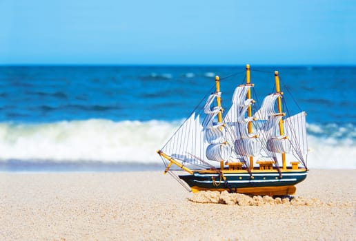 Model of a ship floats on the beach. Vacation conceptual image.