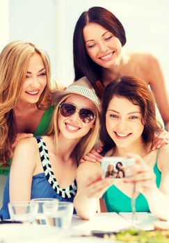 summer holidays and vacation - girls taking photo in cafe on the beach