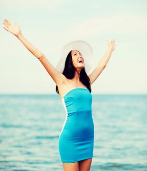 summer holidays and vacation - girl with hands up on the beach