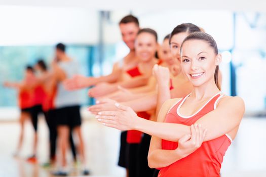 fitness, sport, training, gym and lifestyle concept - group of smiling people stretching in the gym