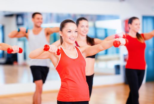 fitness, sport, training, gym and lifestyle concept - group of smiling people working out with dumbbells in the gym