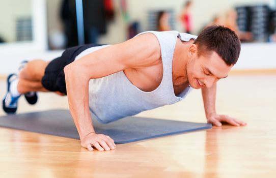 fitness, sport, training, gym and lifestyle concept - smiling man doing push-ups in the gym