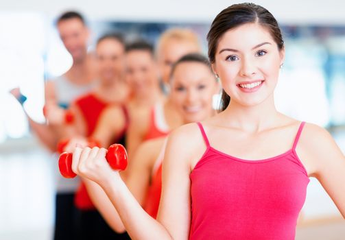 fitness, sport, training, gym and lifestyle concept - group of smiling people lifting dumbbells in the gym