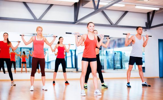 fitness, sport, training, gym and lifestyle concept - group of smiling people working out with barbells in the gym