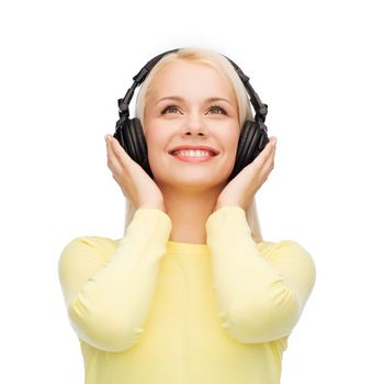 music and technology concept - smiling young woman listening to music with headphones
