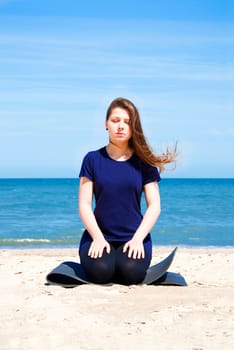Mental health. Young woman practicing yoga at sea. 