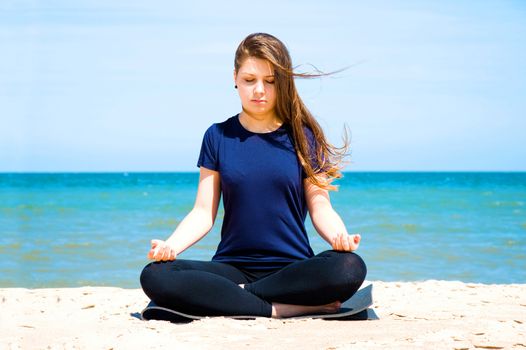 Mental health. Young woman practicing yoga at sea. 