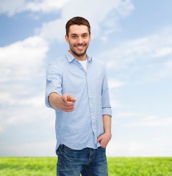 happiness and people concept - smiling man pointing finger at you