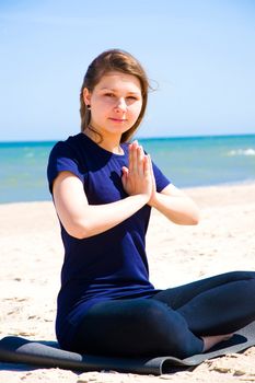 Mental health. Young woman practicing yoga at sea. 